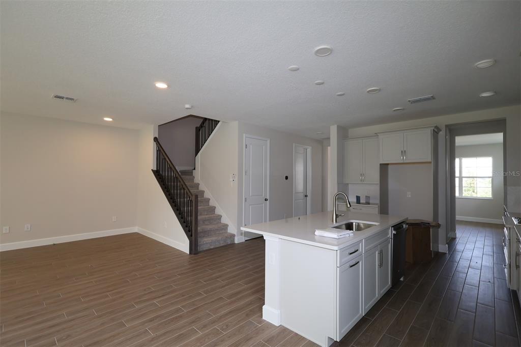 A modern kitchen with light gray cabinets, a central island, and wood-look tile flooring — 1284 HYDE STREET, ST CLOUD, FL