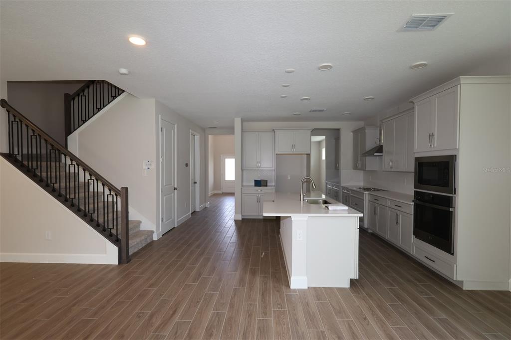 A modern kitchen features light-colored cabinetry, a central island, and wood-look tile flooring — 1284 HYDE STREET, ST CLOUD, FL