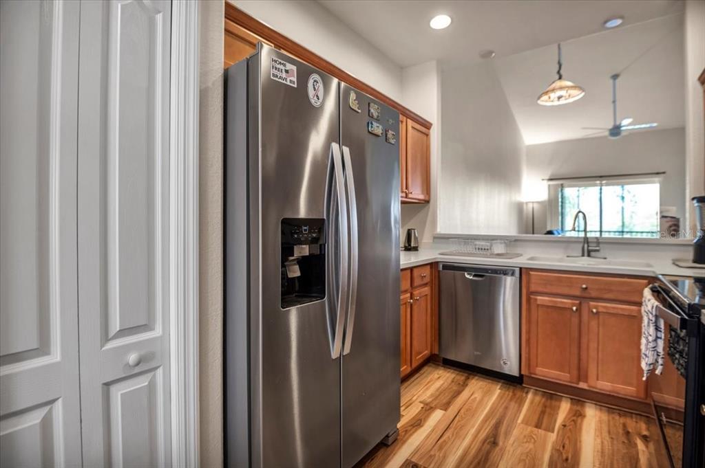 A kitchen features stainless steel appliances, wood cabinets, and wood-look flooring — 1003 FAIRWAYCOVE LANE UNIT 205, BRADENTON, FL