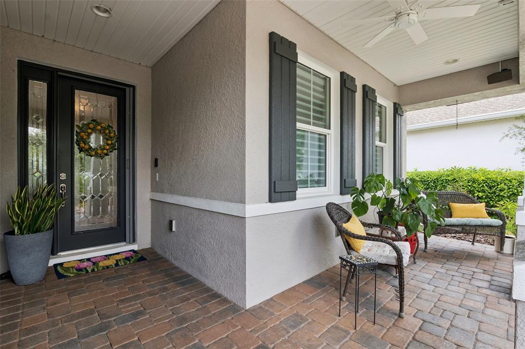 A covered front porch features brick pavers, a dark front door, and outdoor seating — 965 AVERY MEADOWS WAY, DELAND, FL