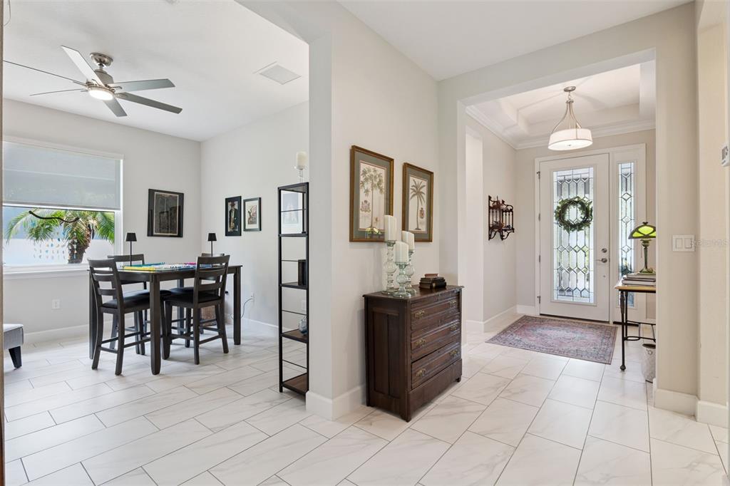 A bright foyer with white tile floors leads into a dining area with a ceiling fan — 965 AVERY MEADOWS WAY, DELAND, FL