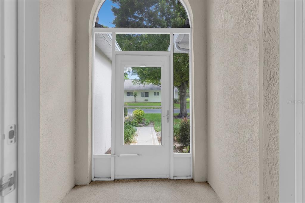 A white screen door leads from a covered entryway to a view of the outdoors — 4390 SAMBOURNE STREET, CLERMONT, FL