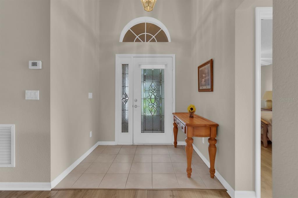 An entryway features a tiled floor, a decorative glass front door, and a wooden console table — 4390 SAMBOURNE STREET, CLERMONT, FL