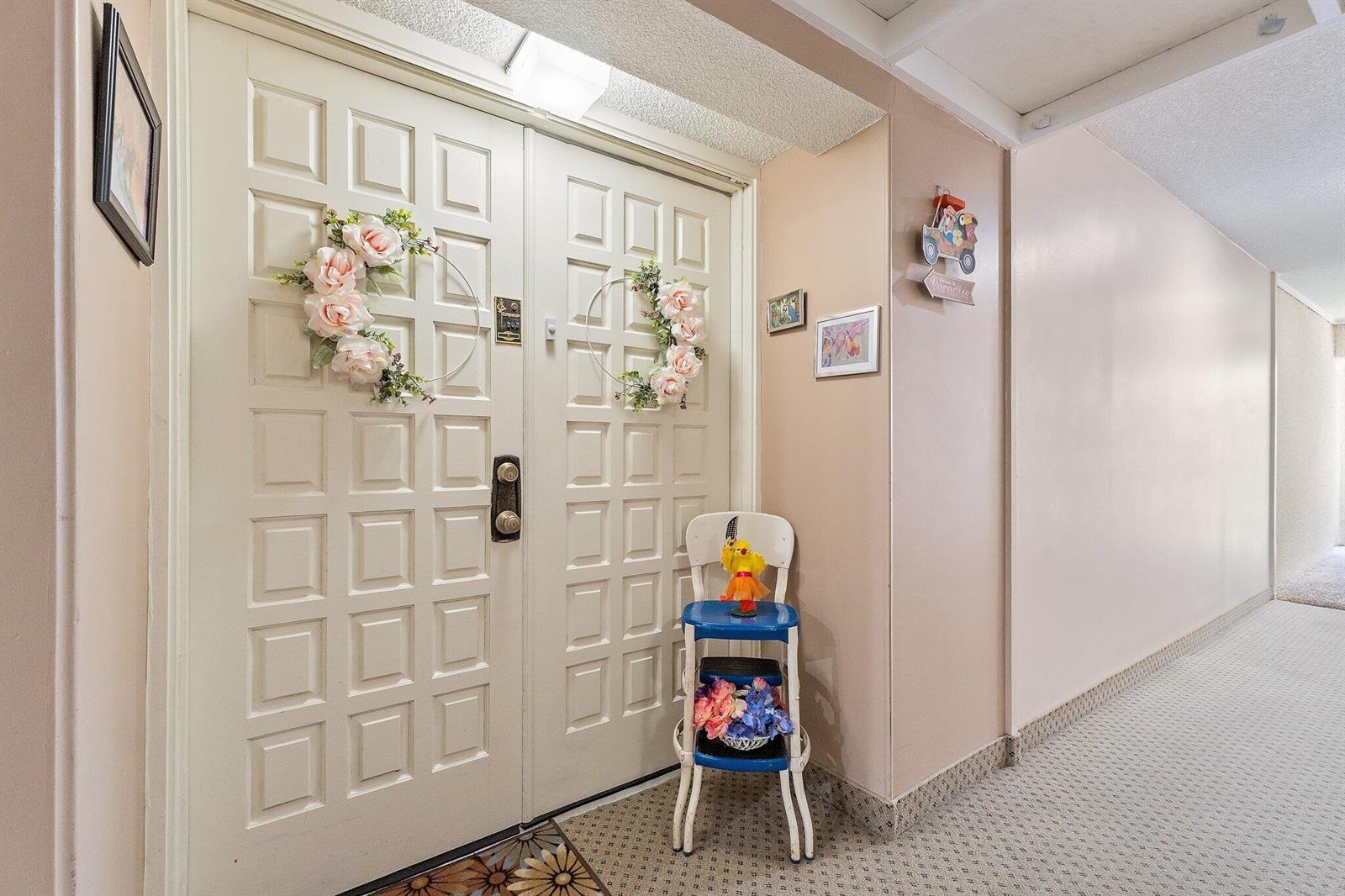 A hallway features a double door with floral wreaths and a small blue tiered chair — 1800 SE Saint Lucie Boulevard # 203, Stuart FL 34996, STUART, FL