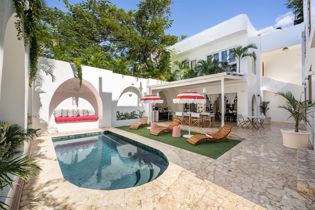 An outdoor patio features a swimming pool, lounge chairs, red-striped umbrellas, and a covered dining area — 1507 MIRSONIA UNIT MIR, SAN JUAN, PR