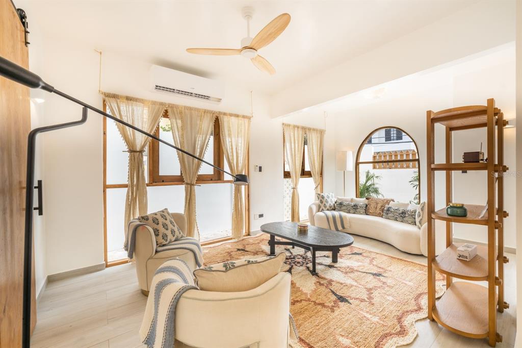 A bright living room features a curved sofa, two armchairs, a patterned rug, and arched windows — 1507 MIRSONIA UNIT MIR, SAN JUAN, PR