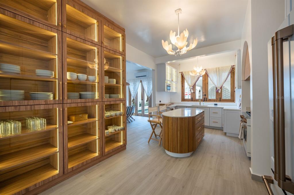 A kitchen features wood-paneled cabinetry, a central island, and glass-fronted display shelves with interior lighting — 1507 MIRSONIA UNIT MIR, SAN JUAN, PR