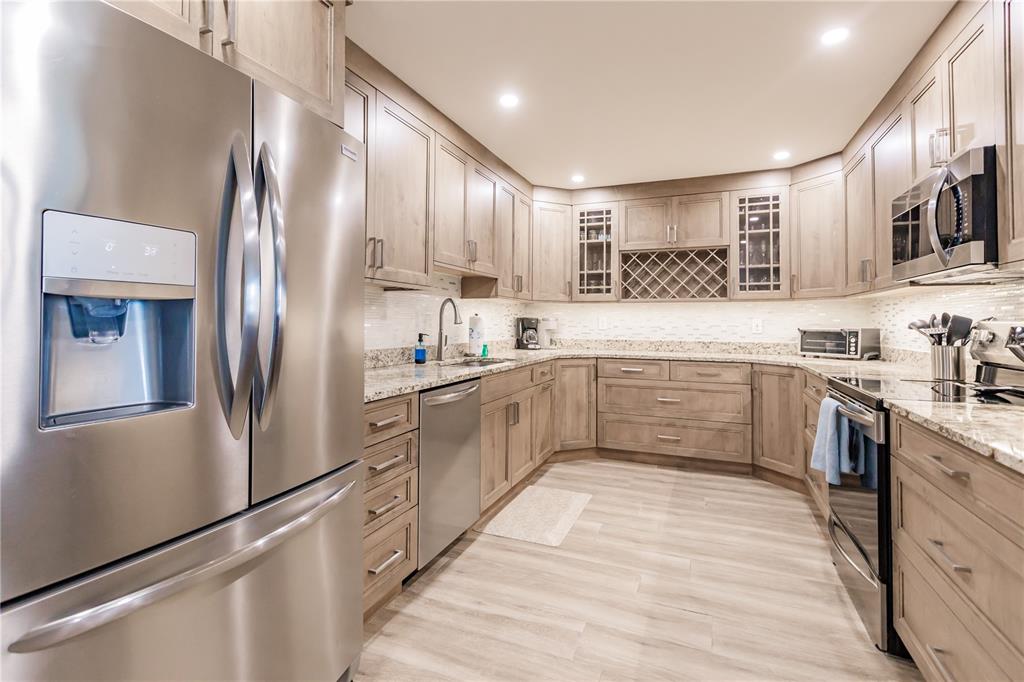 A kitchen with light wood cabinets, stainless steel appliances, and granite countertops — 1200 E PEPPERTREE LANE UNIT 602, SARASOTA, FL