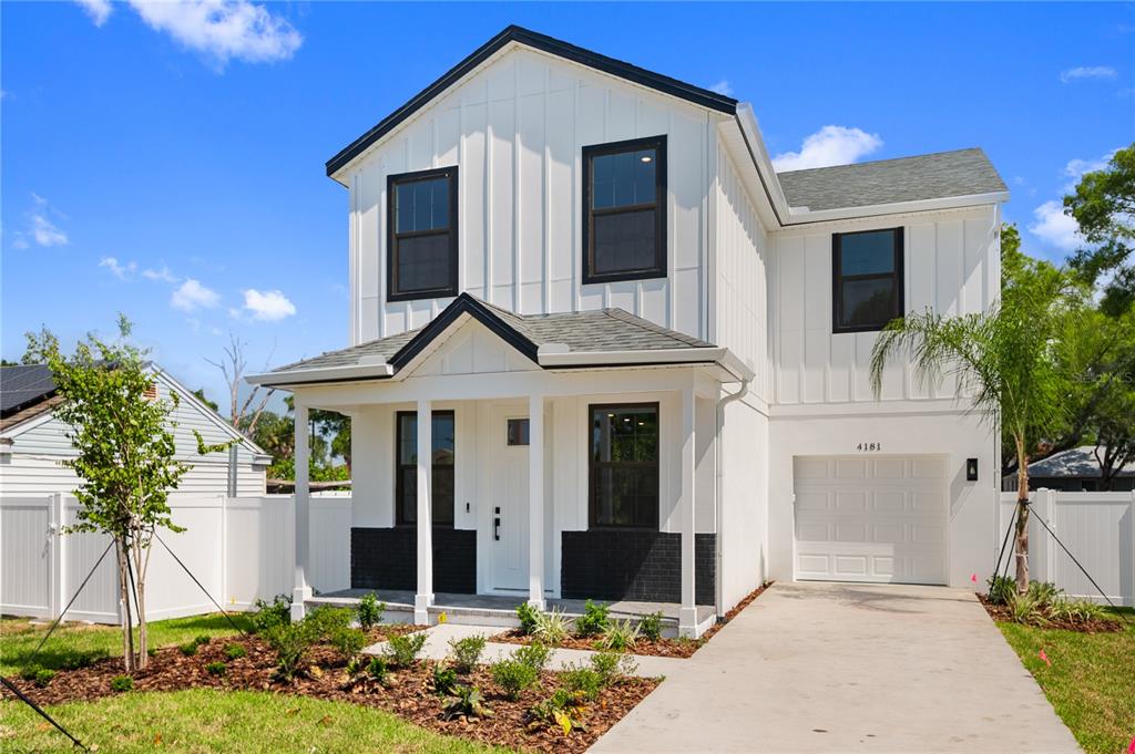 A two-story house with white vertical siding, black window frames, and a front porch — 4181 56TH AVENUE N, ST PETERSBURG, FL