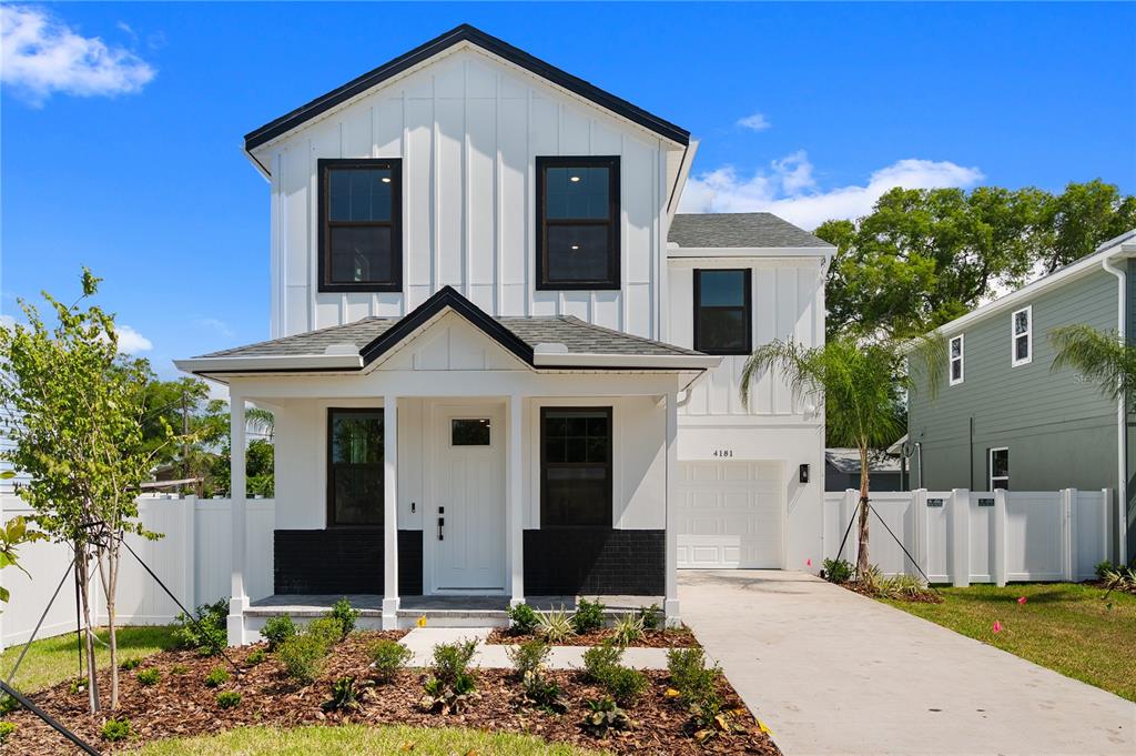 A two-story house with white vertical siding, black window frames, and a front porch — 4181 56TH AVENUE N, ST PETERSBURG, FL