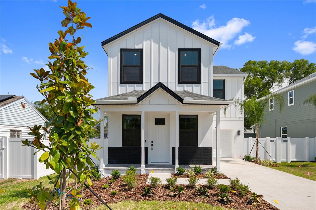 A two-story house with white vertical siding, black window frames, and a front porch — 4181 56TH AVENUE N, ST PETERSBURG, FL