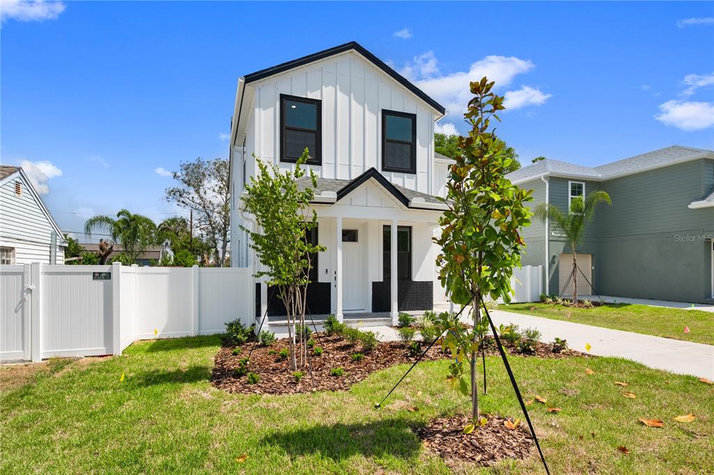 A two-story white house with black trim and a small front porch stands outdoors — 4181 56TH AVENUE N, ST PETERSBURG, FL