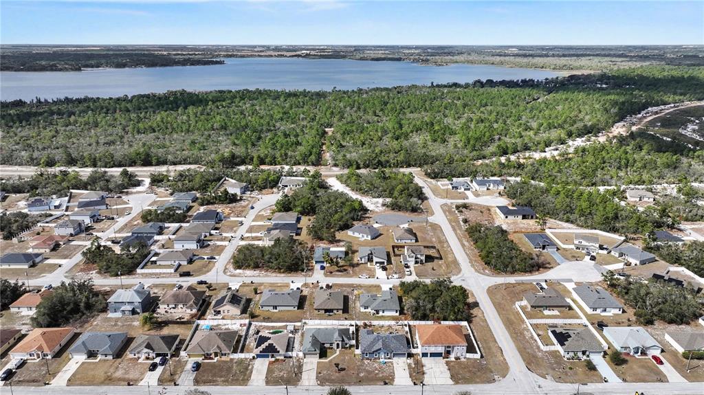 An aerial view shows a suburban neighborhood with single-family homes near a large lake — 611 AMAZON COURT, POINCIANA, FL