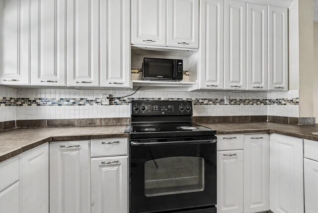A kitchen features white cabinets, a black stove, a microwave, and a tiled backsplash — 8327 Fairway Road # 8327, Sunrise FL 33351, SUNRISE, FL