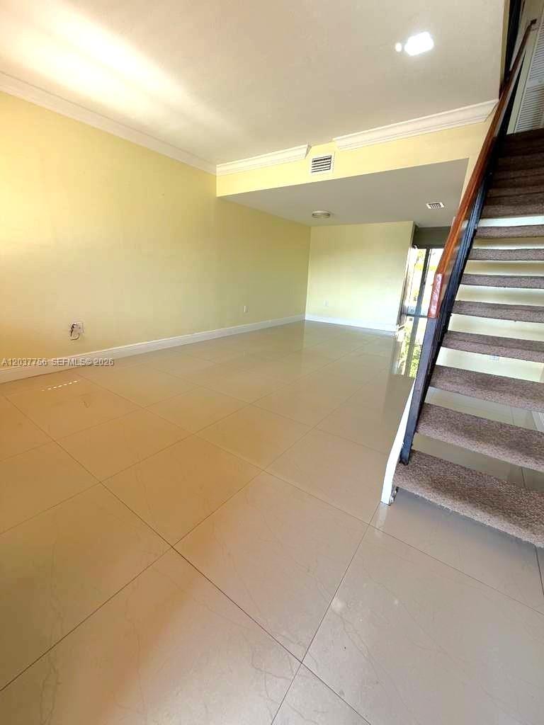 A room with light yellow walls, tile flooring, and a carpeted staircase with railings — 680 NW 82nd. Pl. # 261, Miami FL 33126, MIAMI, FL