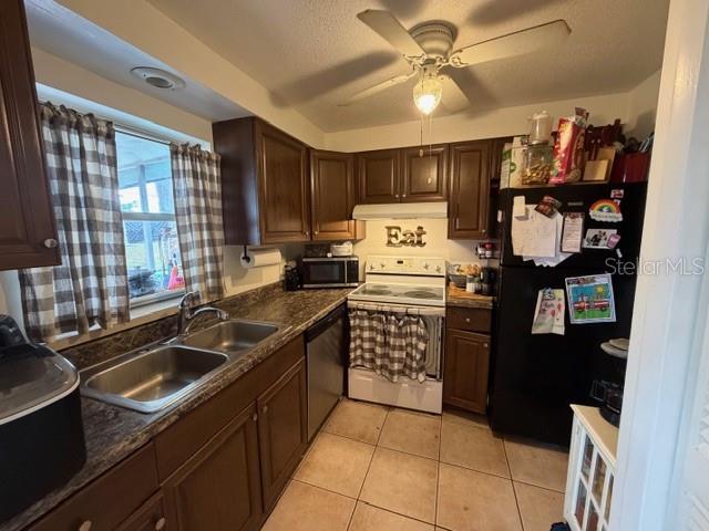 A kitchen features dark wood cabinets, a double sink, a black refrigerator, and a ceiling fan — 551 GROVE AVENUE NW, PORT CHARLOTTE, FL