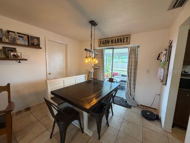 A dining area features a dark wood table, metal chairs, a bench, and pendant lighting — 551 GROVE AVENUE NW, PORT CHARLOTTE, FL