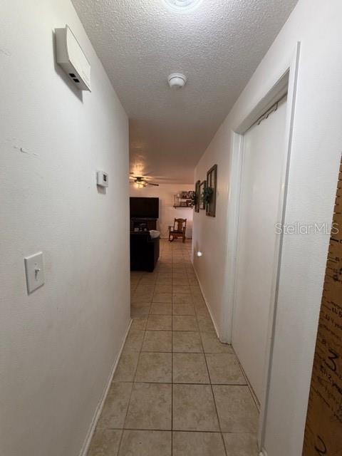 A hallway with tile flooring leads toward a living area with a television and chair — 551 GROVE AVENUE NW, PORT CHARLOTTE, FL