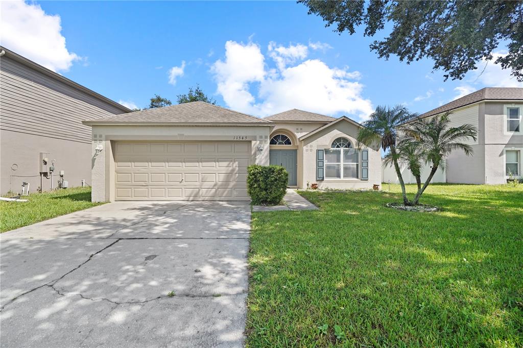 A single-story house with a beige exterior, a two-car garage, and a front lawn — 11545 BENTRY STREET, ORLANDO, FL