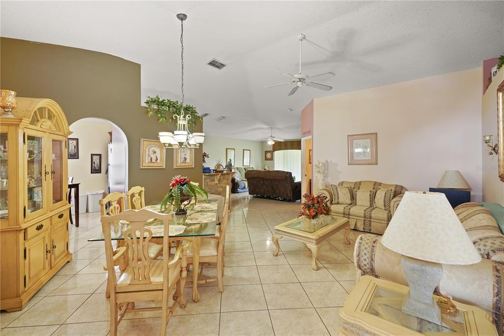 An open-concept living and dining area features tile flooring, vaulted ceilings, and light-colored furniture — 11545 BENTRY STREET, ORLANDO, FL