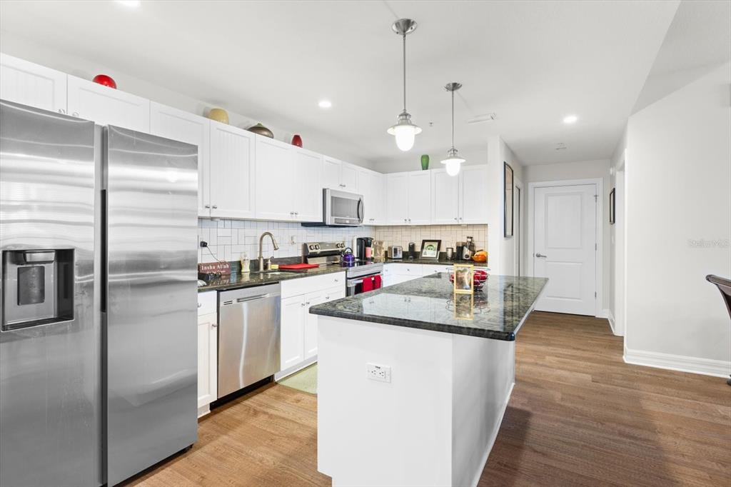A kitchen features white cabinets, stainless steel appliances, a granite island, and wood-look flooring — 536 BAHIA BEACH BOULEVARD UNIT 503A, RUSKIN, FL