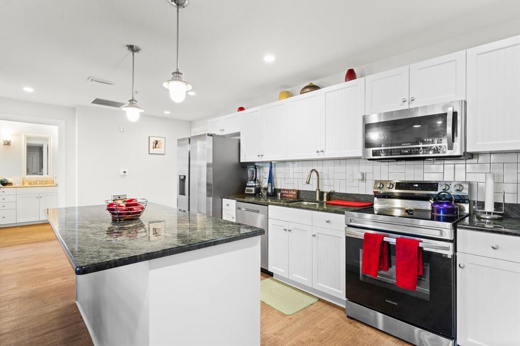 A kitchen features white cabinets, dark granite countertops, stainless steel appliances, and a central island — 536 BAHIA BEACH BOULEVARD UNIT 503A, RUSKIN, FL
