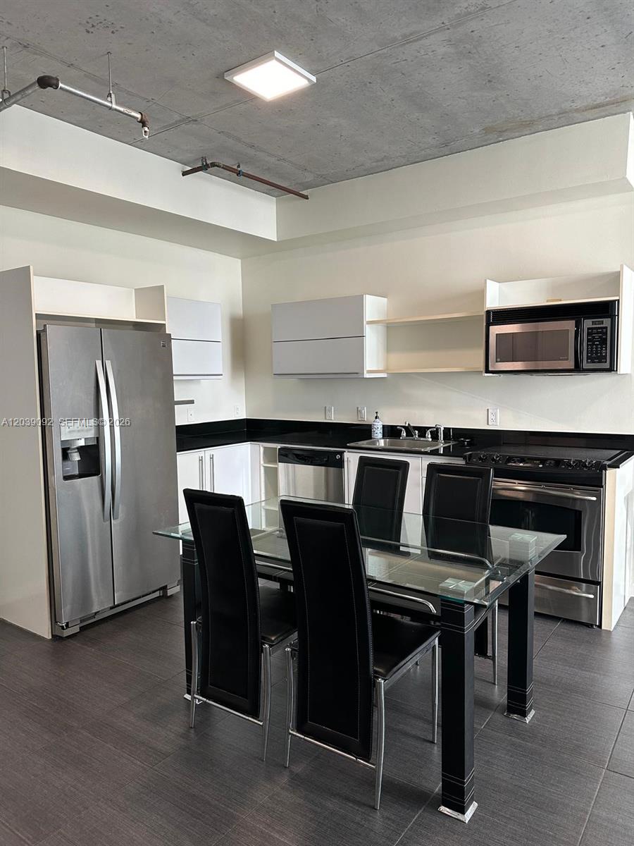 A kitchen features stainless steel appliances, dark countertops, and a dining table with black chairs — 690 SW 1st Ct # 2328, Miami FL 33130, MIAMI, FL