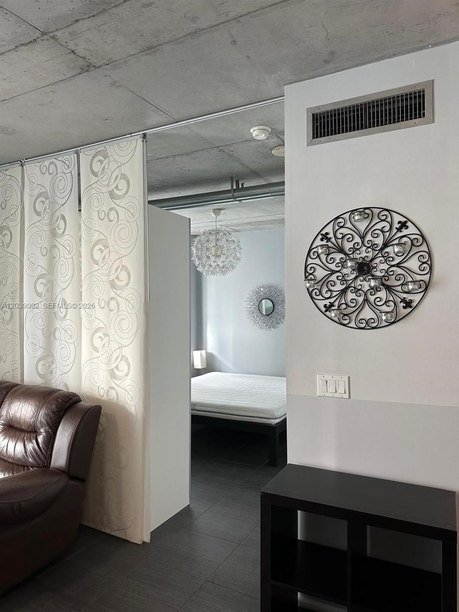 A living area with a curtain partition leads to a bedroom with a concrete ceiling — 690 SW 1st Ct # 2328, Miami FL 33130, MIAMI, FL