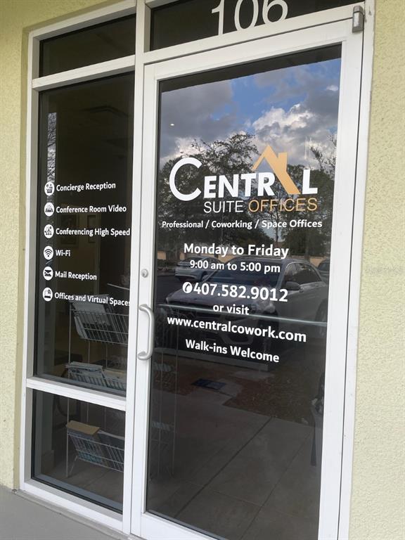 The glass front door of a business suite displays office hours and contact information — 12250 MENTA STREET UNIT 105, ORLANDO, FL