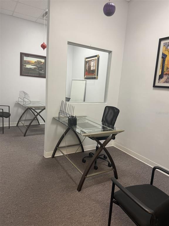 An office space features two glass-topped desks, black chairs, and framed artwork on the walls — 12250 MENTA STREET UNIT 105, ORLANDO, FL
