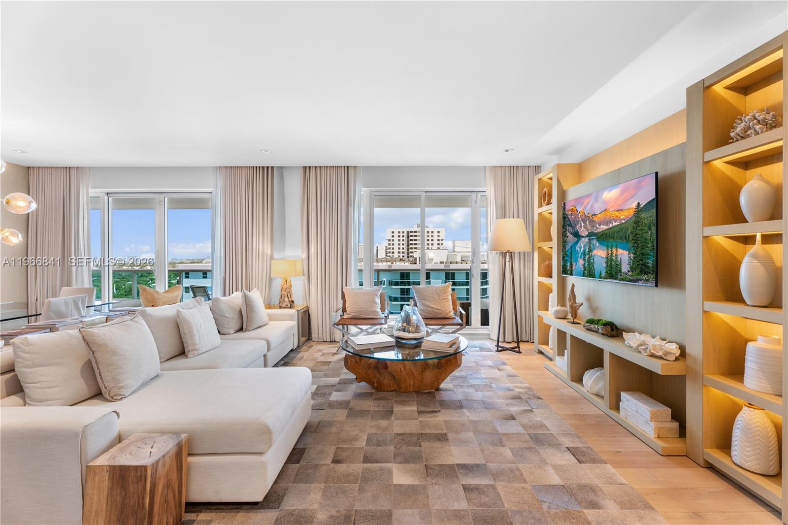 A modern living room features a large sectional sofa, a wood-base coffee table, and shelving — 102 24th St # 1705, Miami Beach FL 33139, MIAMI BEACH, FL