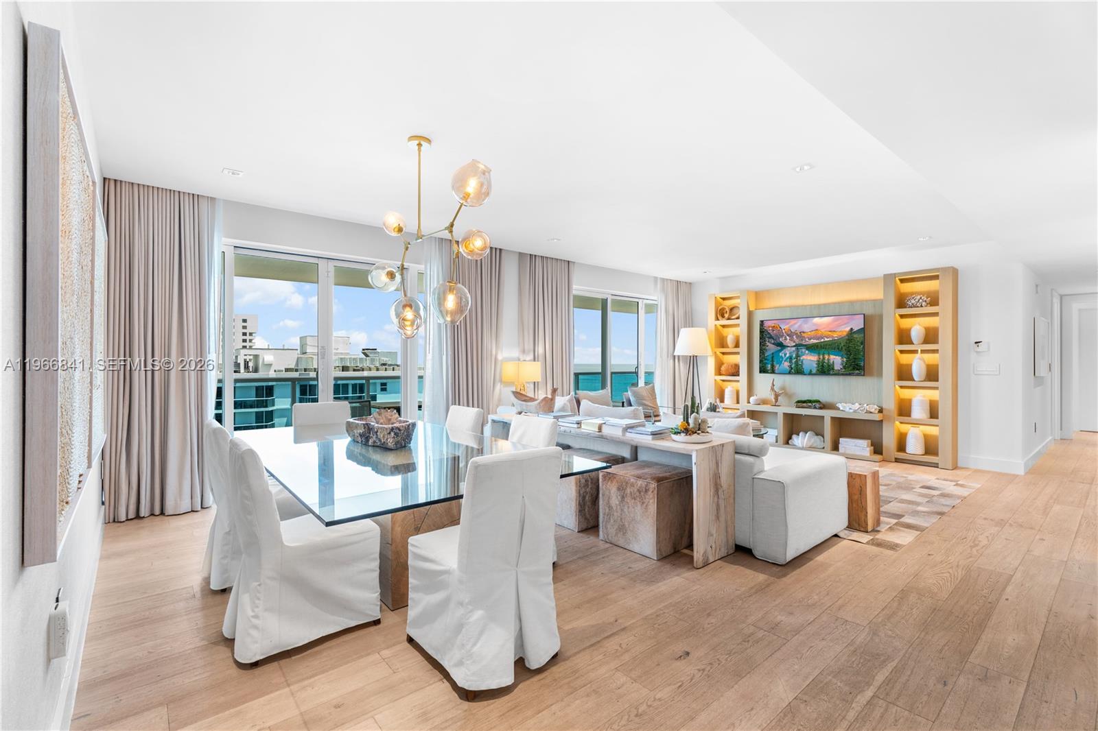 A bright, open-concept living and dining area features white slipcovered chairs, a glass table, and ocean views — 102 24th St # 1705, Miami Beach FL 33139, MIAMI BEACH, FL