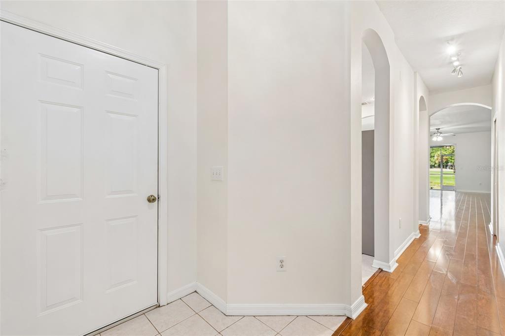 An entryway with a white door, tile flooring, and a hallway leading to a living area — 18107 NASSAU POINT DR, TAMPA, FL
