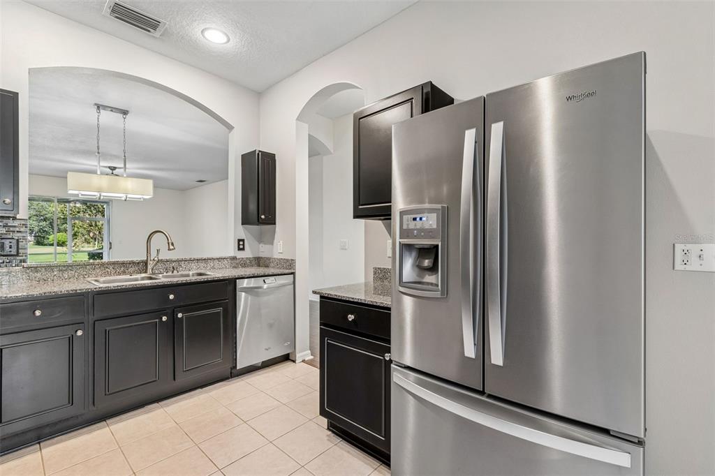 A kitchen features dark cabinets, granite countertops, stainless steel appliances, and tile flooring — 18107 NASSAU POINT DR, TAMPA, FL