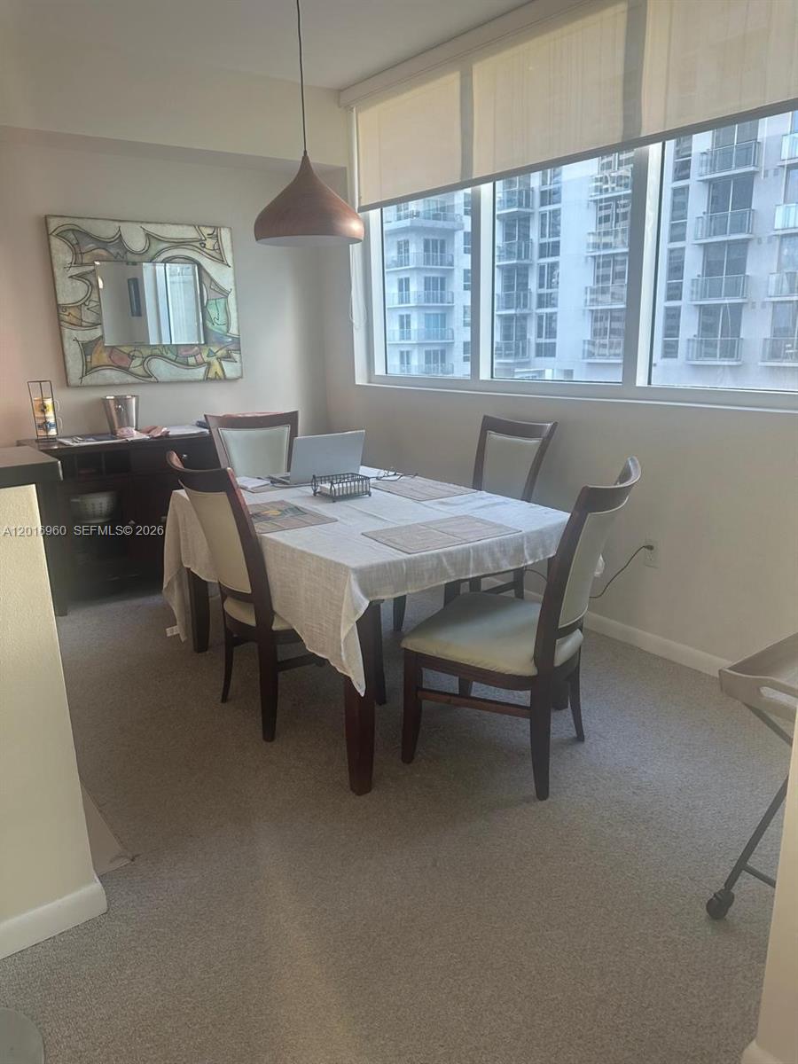 A dining room features a table with four chairs, a pendant light, and large windows — 253 NE 2nd St # 1402, Miami FL 33132, MIAMI, FL
