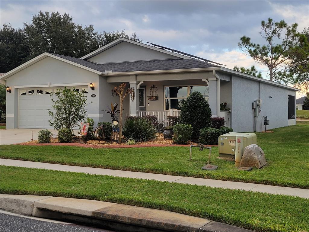 A single-story house with a gray exterior, a two-car garage, and a landscaped front yard — 27343 ROANOKE DRIVE, LEESBURG, FL