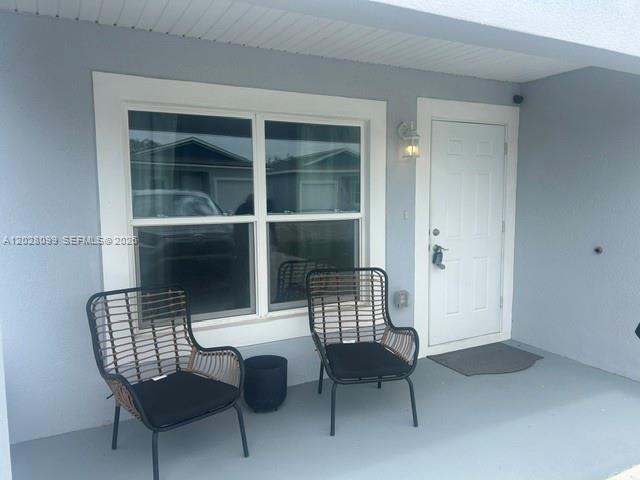 A covered porch features two wicker chairs, a small side table, and a white door — 1497 Las Villas Blvd, Sebring FL 33870, SEBRING, FL