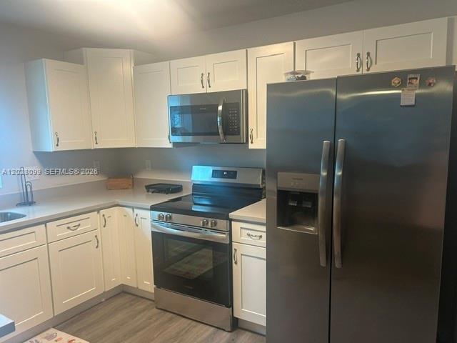 A kitchen features white cabinets, stainless steel appliances, and light-colored countertops — 1497 Las Villas Blvd, Sebring FL 33870, SEBRING, FL