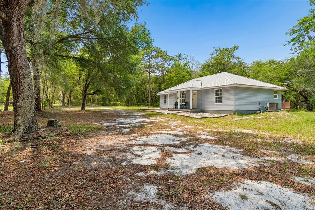 A light blue, single-story house with a metal roof sits on a sandy, wooded lot — 8855 SW 146TH PLACE, DUNNELLON, FL