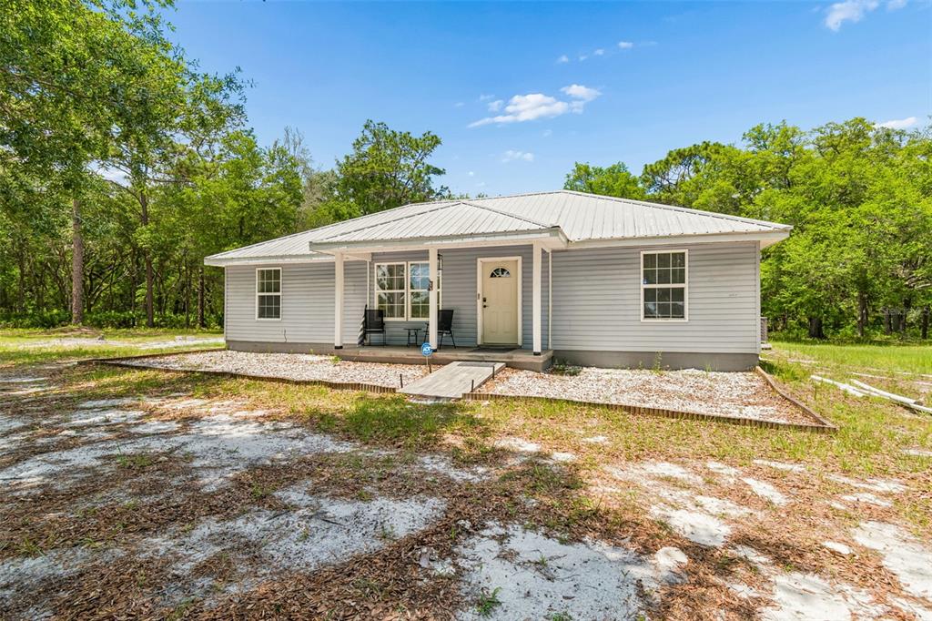 A single-story house with light blue siding, a metal roof, and a front porch — 8855 SW 146TH PLACE, DUNNELLON, FL