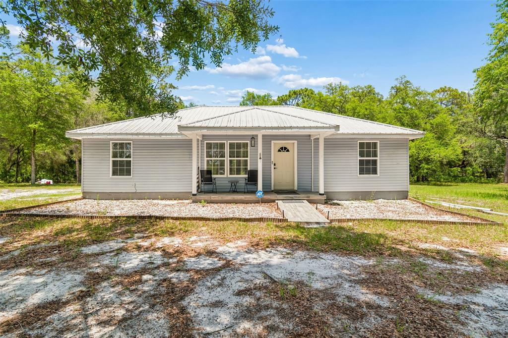 A single-story house with light gray siding and a metal roof sits on a lot — 8855 SW 146TH PLACE, DUNNELLON, FL