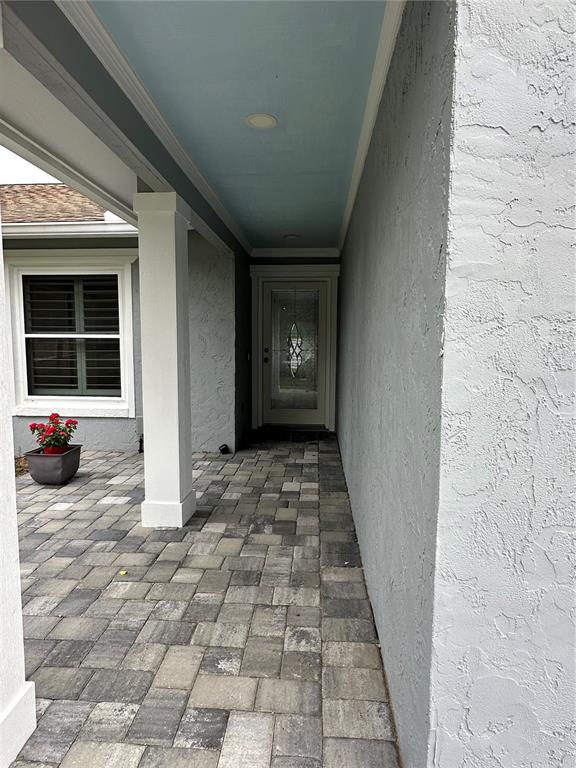 A covered entryway features a paver floor, a white pillar, and a light blue ceiling — 1229 ALLENDALE DRIVE, OVIEDO, FL
