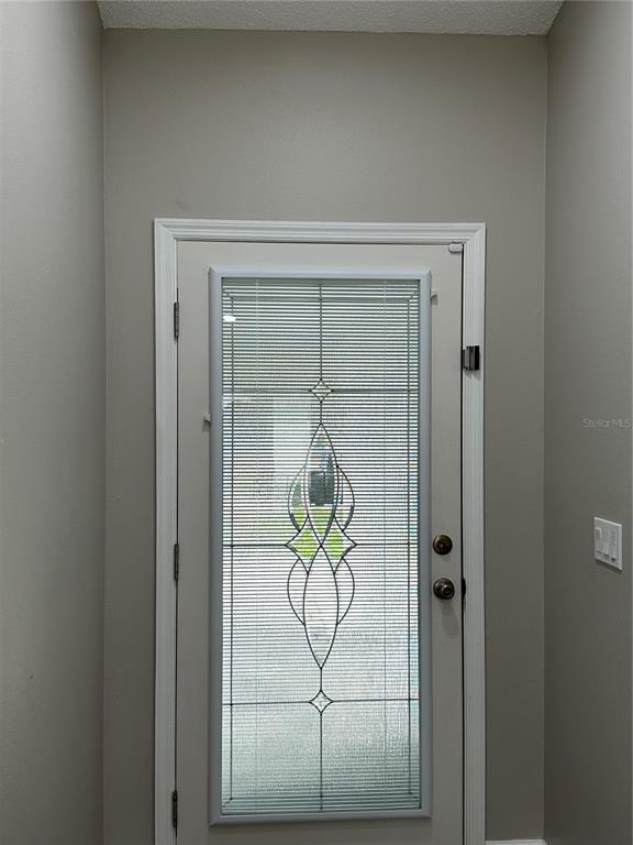A light-colored front door with a decorative glass insert featuring integrated blinds — 1229 ALLENDALE DRIVE, OVIEDO, FL