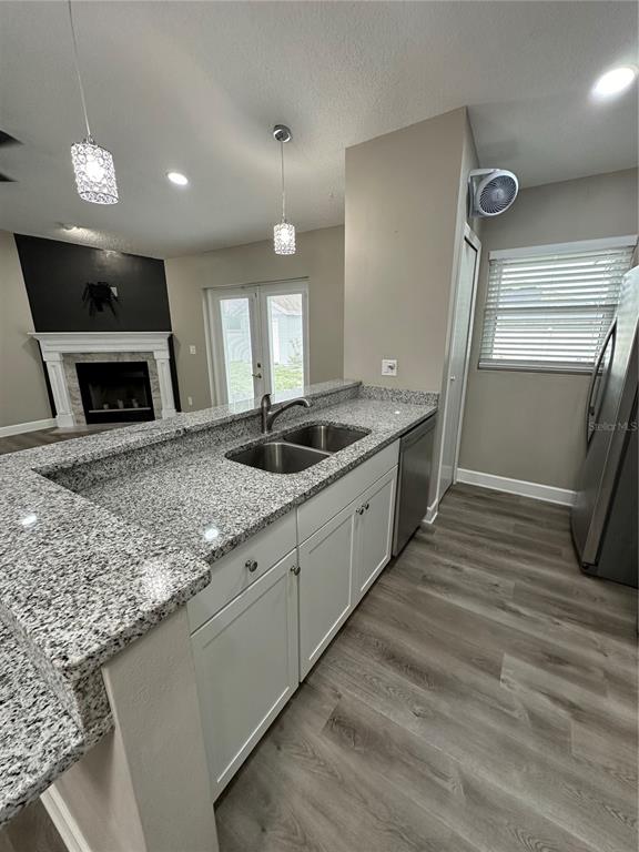 A kitchen features granite countertops, white cabinets, stainless steel appliances, and wood-look flooring — 1229 ALLENDALE DRIVE, OVIEDO, FL