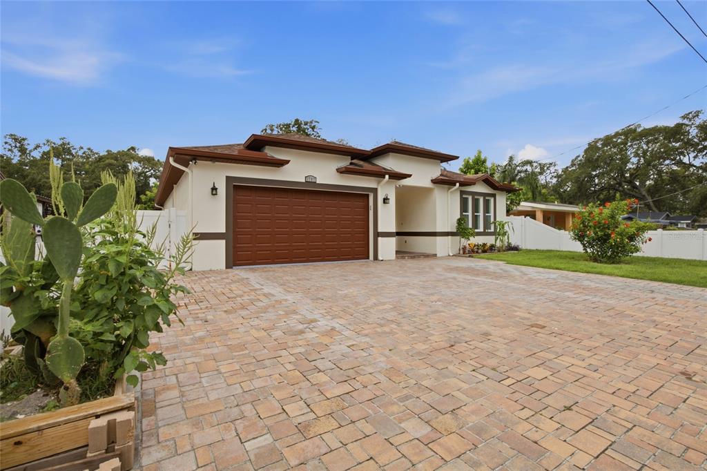 A single-story house with a brown garage door and a large paved driveway — 1707 E EMMA STREET, TAMPA, FL