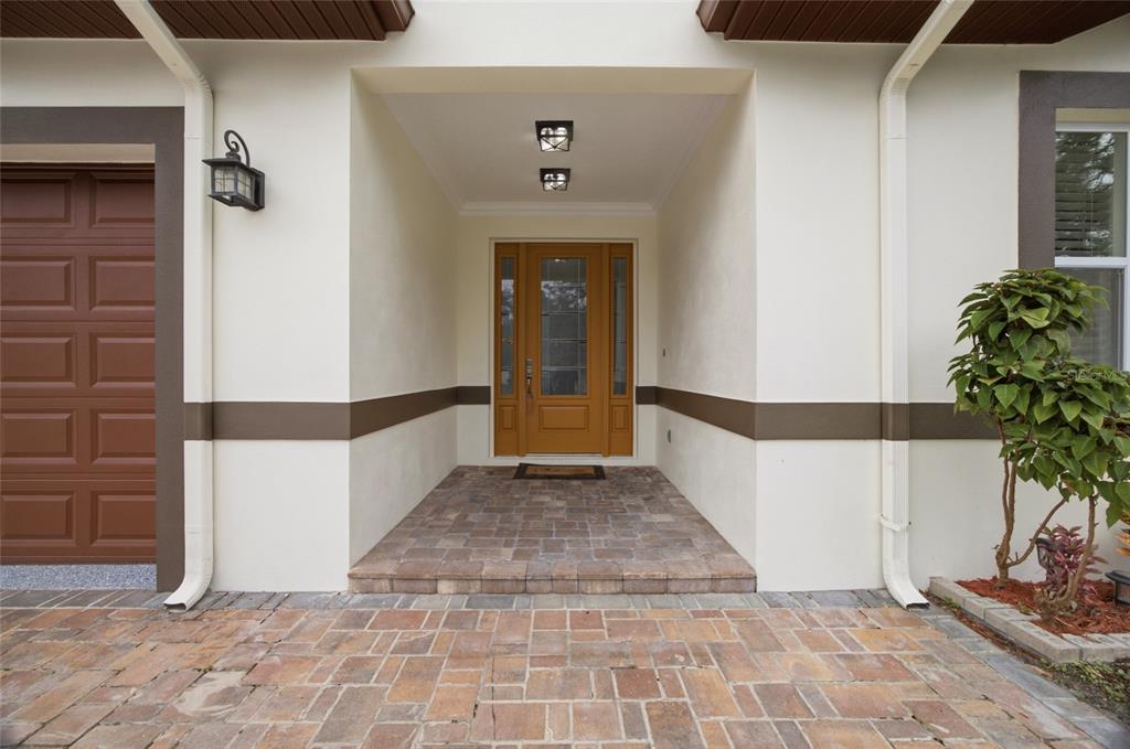 A front entryway features a paved porch, a wooden front door, and cream-colored stucco walls — 1707 E EMMA STREET, TAMPA, FL
