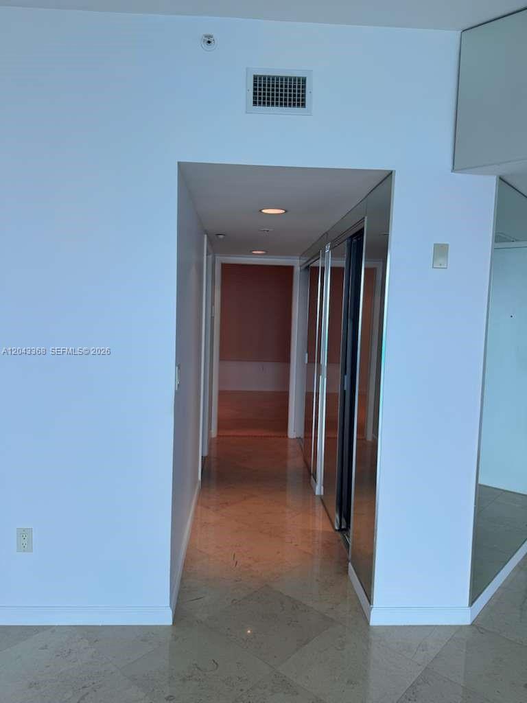 A hallway with light-colored tile flooring leads to an interior room with mirrored closet doors — 5025 Collins Ave # 1602, Miami Beach FL 33140, MIAMI BEACH, FL