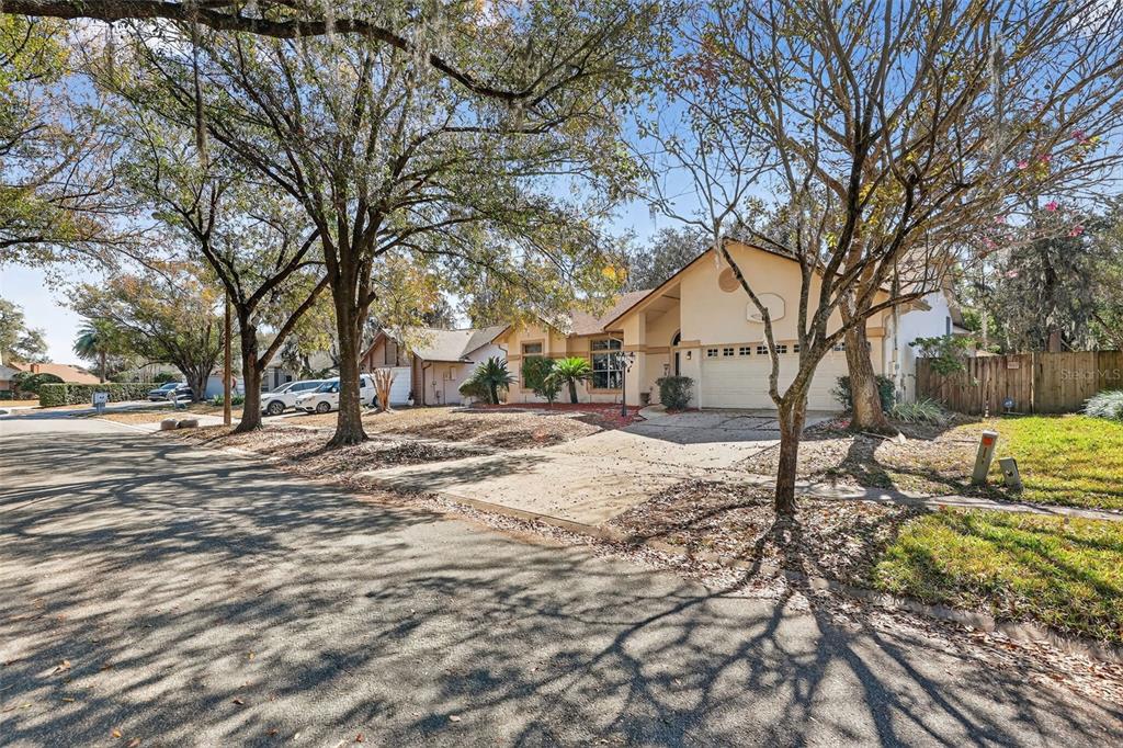 A single-story suburban house with a concrete driveway, a two-car garage, and mature shade trees — 3236 PAISLEY CIRCLE, ORLANDO, FL