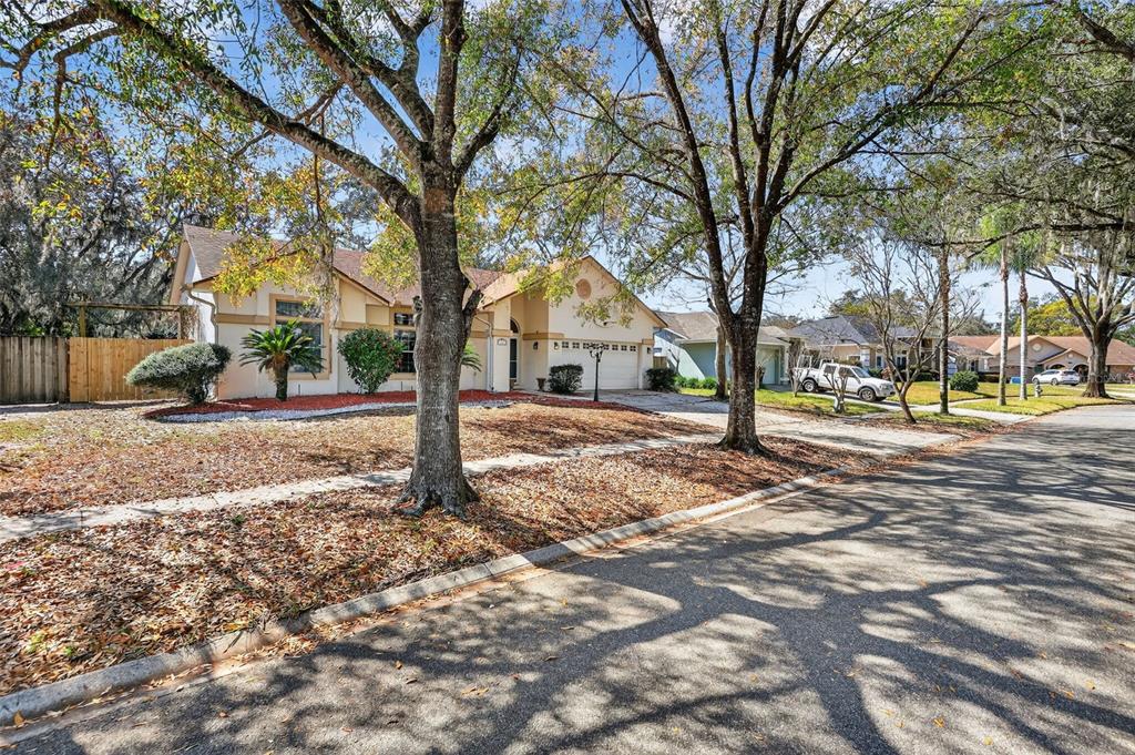 A single-story suburban house with a tan exterior, a two-car garage, and mature trees — 3236 PAISLEY CIRCLE, ORLANDO, FL