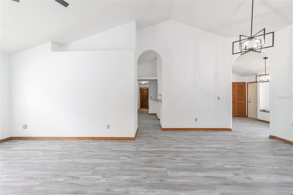 An interior view of a room with white walls, vaulted ceilings, and gray wood-look flooring — 13984 SW 80TH STREET, DUNNELLON, FL